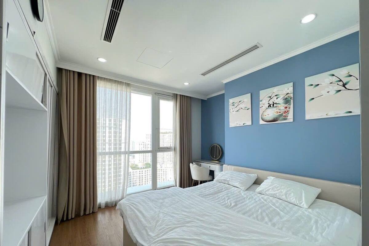 A modern hotel room with a large bed, a desk, and a view of the city.