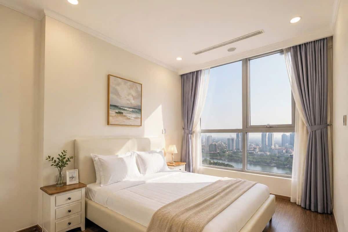 A hotel room with a large bed, a nightstand, a bedside table, a window with curtains, and a city view.