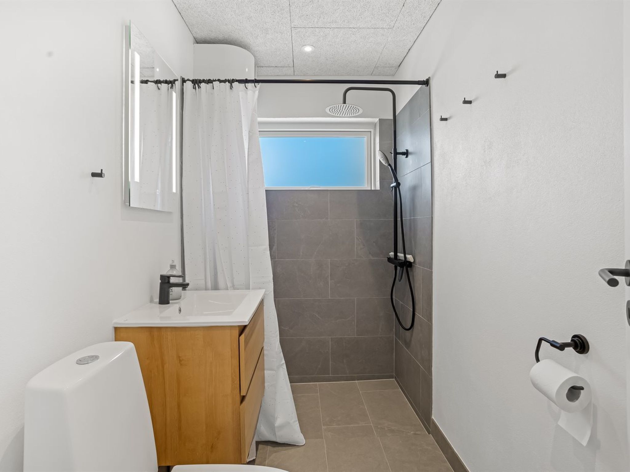 A compact bathroom with a shower, a toilet, and a sink.