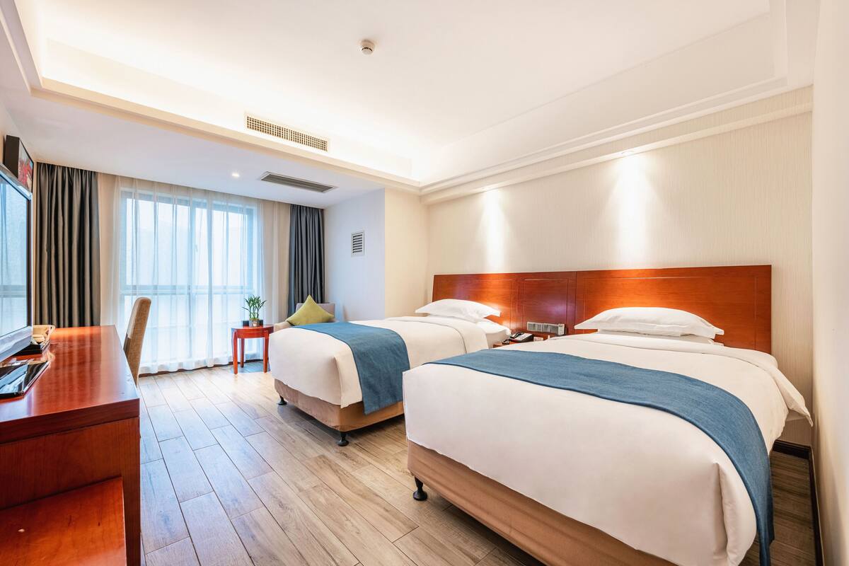 A hotel room with two beds, a desk, and a chair.