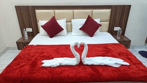Ein Bett mit roter Decke, weißen Kissen und einer Handtuch-Herzanordnung.