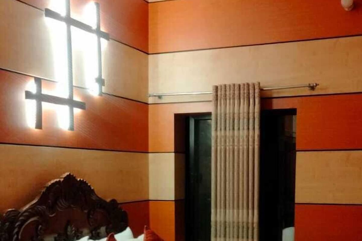 A hotel room with a bed, a ceiling fan, and a window with curtains.
