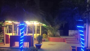 A gazebo with blue LED lights, surrounded by potted plants and a palm tree. - Garden View Villa (Rajshahi)