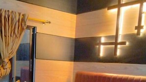 A hotel room with a large bed, a headboard with a cross design, and a wall-mounted light fixture. - Garden View Villa (Rajshahi)