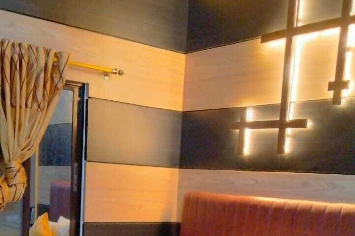 A hotel room with a large bed, a headboard with a cross design, and a wall-mounted light fixture.