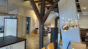 Een moderne keuken met een ingebouwde kookplaat, houten balken en een eethoek met een tafel en stoelen.