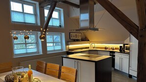 Een moderne keuken met een centraal eiland, houten stoelen en een eettafel.