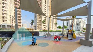 Zona de juegos con equipamiento de ejercicio y un pequeño coche de juguete rojo.