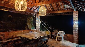 An outdoor patio with a wooden table and benches, surrounded by brick walls and a thatched roof. - Paradisiacal Site in National Park (Teresópolis)