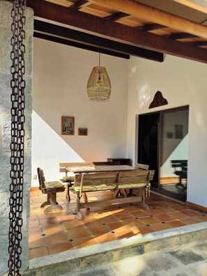 A dining area with a wooden table and benches, a hanging light fixture, and a tiled floor. - Paradisiacal Site in National Park (Teresópolis)