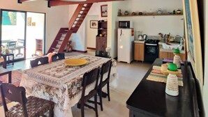 A spacious living area with a high ceiling, a dining table with chairs, a kitchen area with appliances, and a staircase leading to an upper level. - Paradisiacal Site in National Park (Teresópolis)