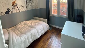 Un dormitorio con cama, un escritorio, una ventana con cortinas y un mural en la pared.
