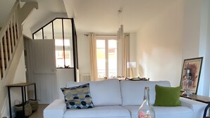 Una sala de estar moderna con un sofá blanco, una mesa de centro redonda y una escalera.