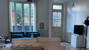 Una habitación amplia con una mesa de madera para comer, sillas amarillas, un sofá y un televisor.