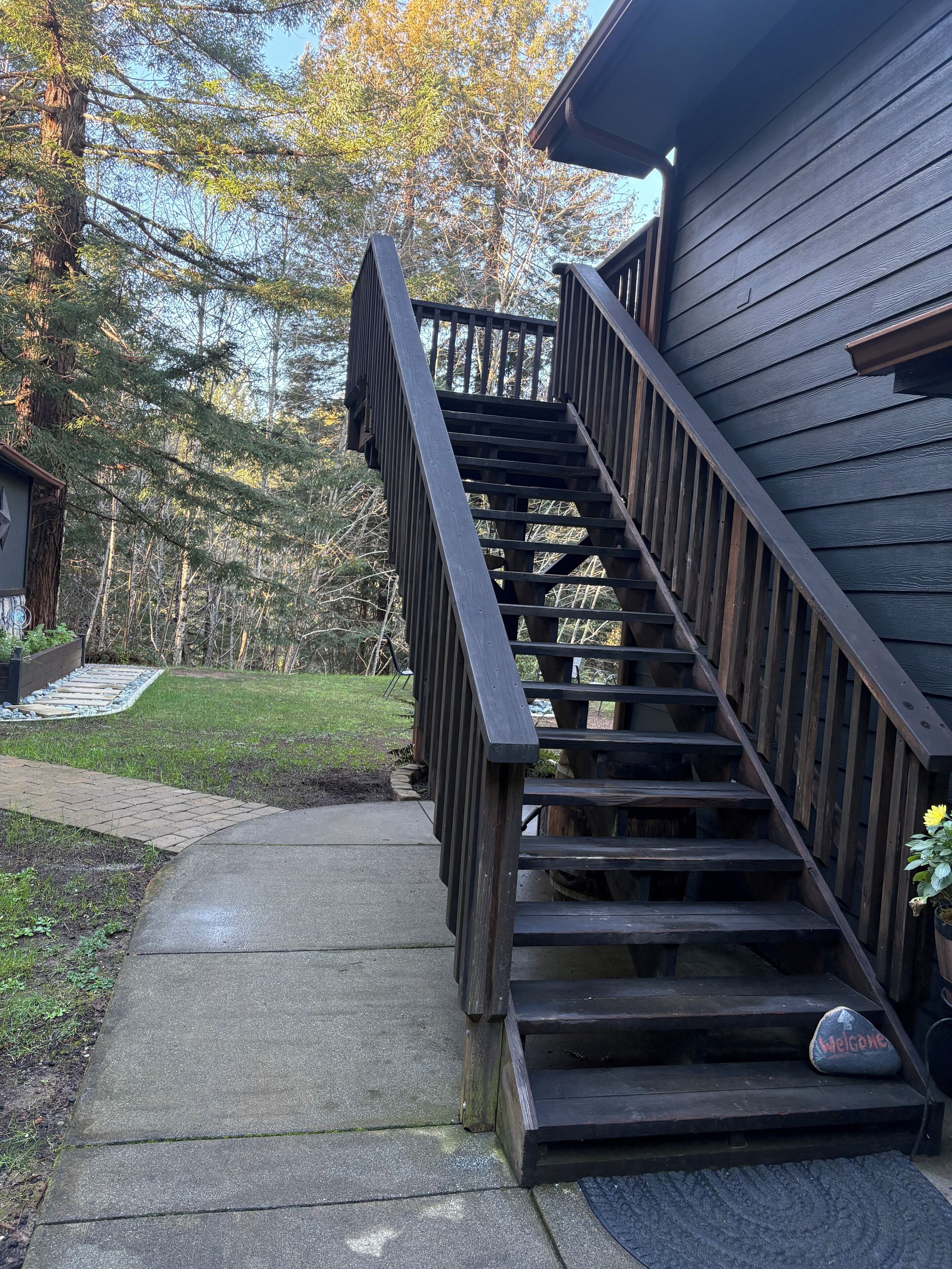 A wooden staircase leading to a house with a 'Welcome' sign on the first step.