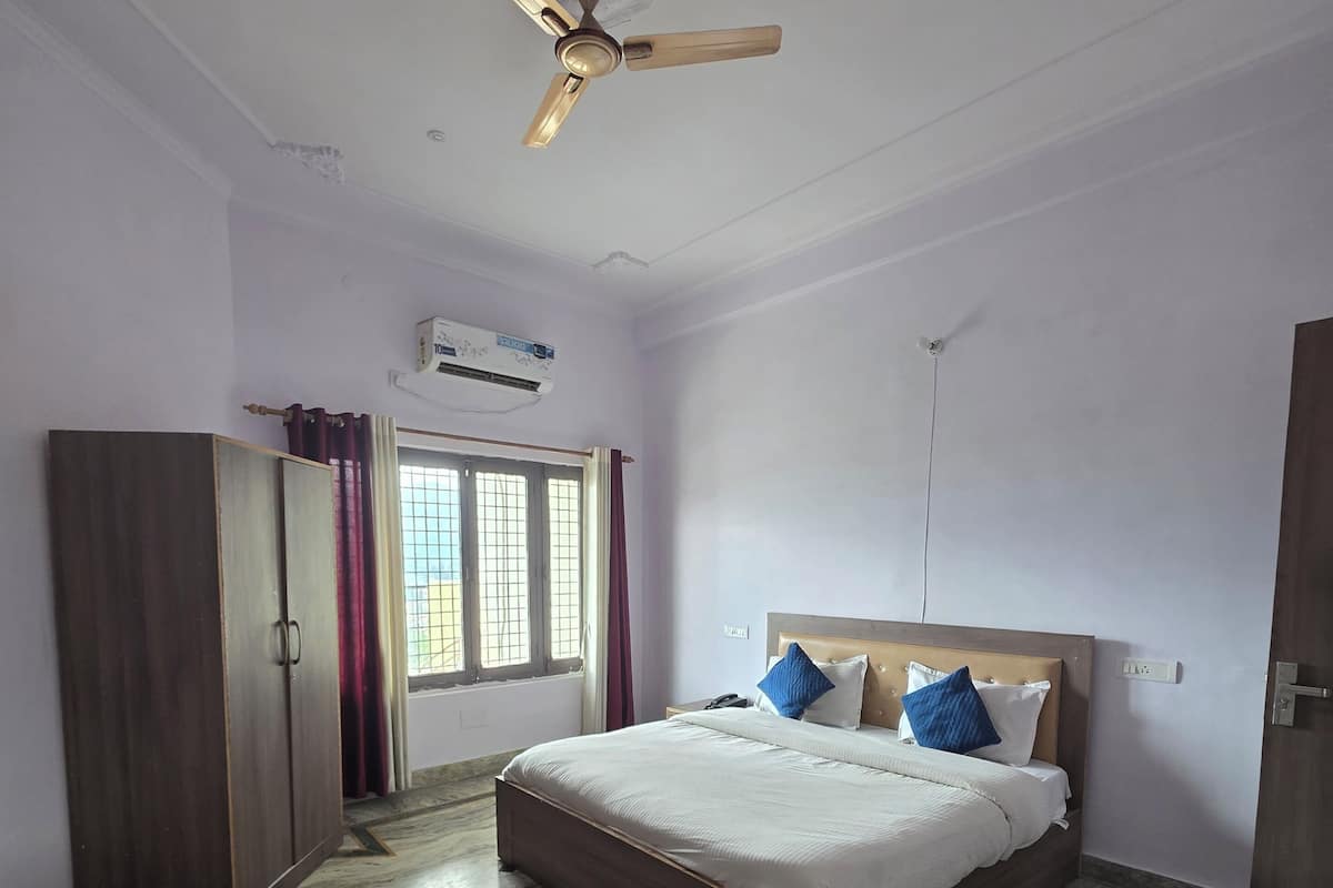Une chambre à coucher comprenant un lit, une armoire, un ventilateur de plafond et une fenêtre avec des rideaux.