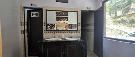 A bathroom with two sinks, a mirror, and a toilet.