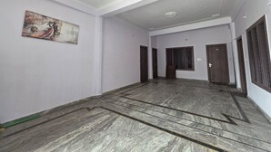 A spacious room with a marble floor, a painting on the wall, and a large window with bars. - SIDDHI VINAYAK HOTEL AND BANQUET (Bhimtal)