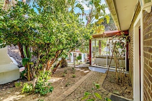 A garden with a brick pathway leading to a covered area with a glass door.