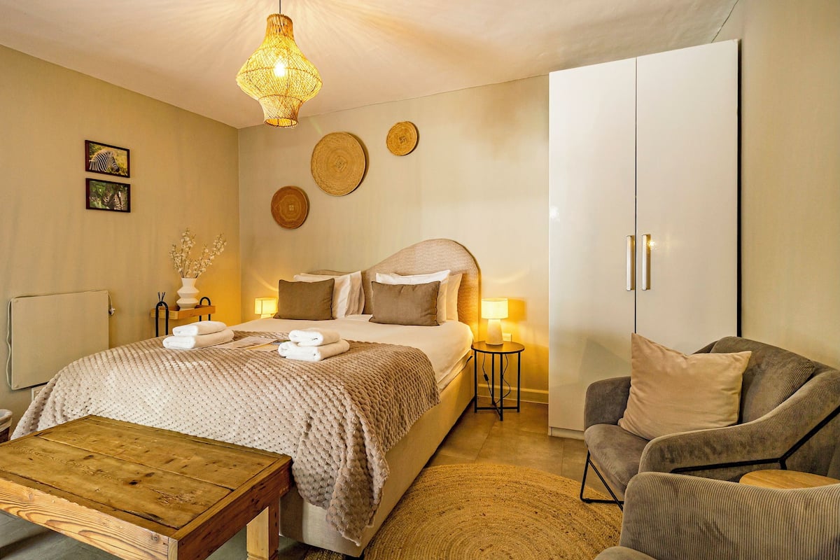A bedroom with a bed, bedside tables, a chair, and a wooden coffee table.