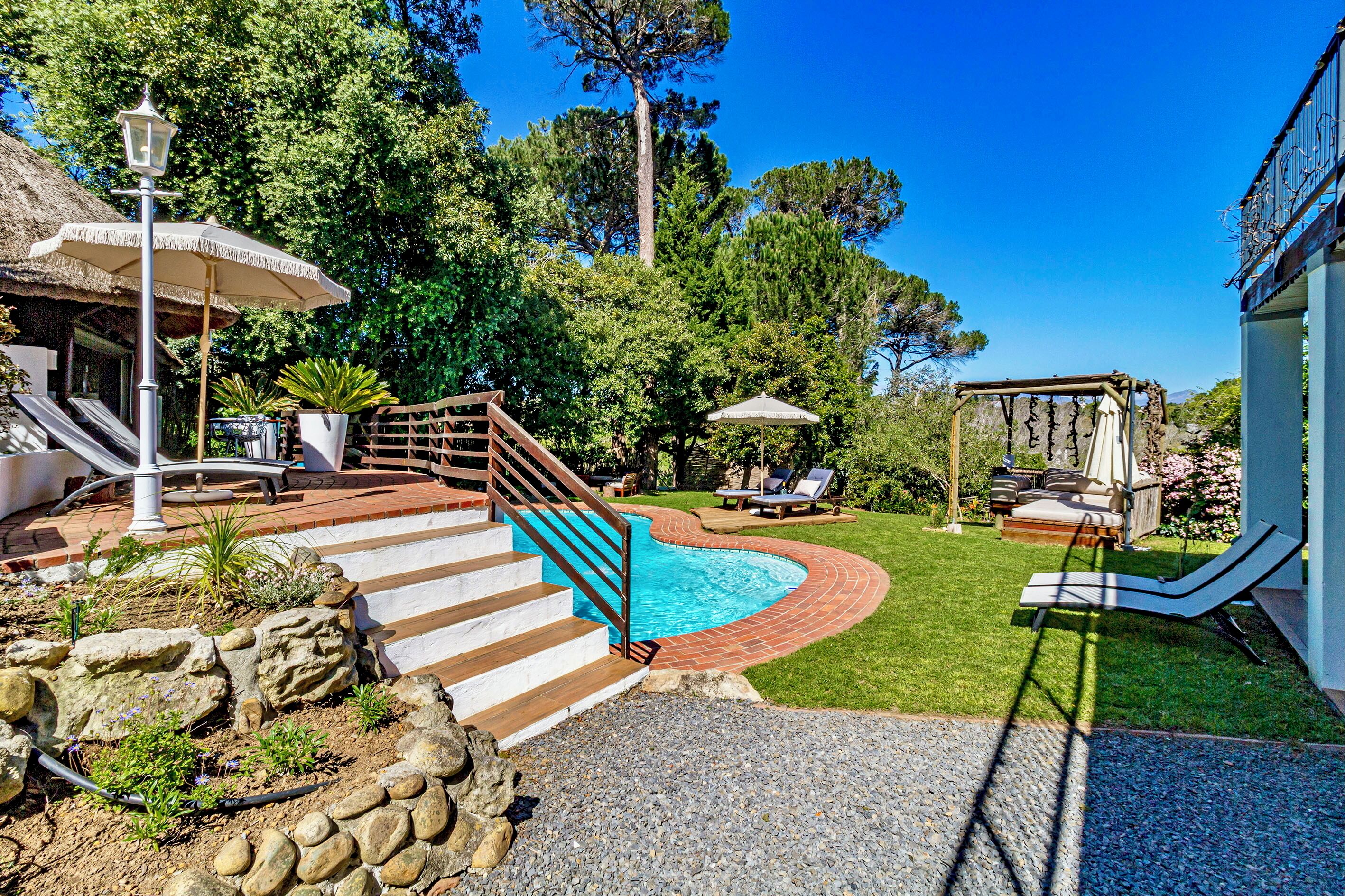 A backyard with a swimming pool, a wooden staircase, and outdoor furniture.