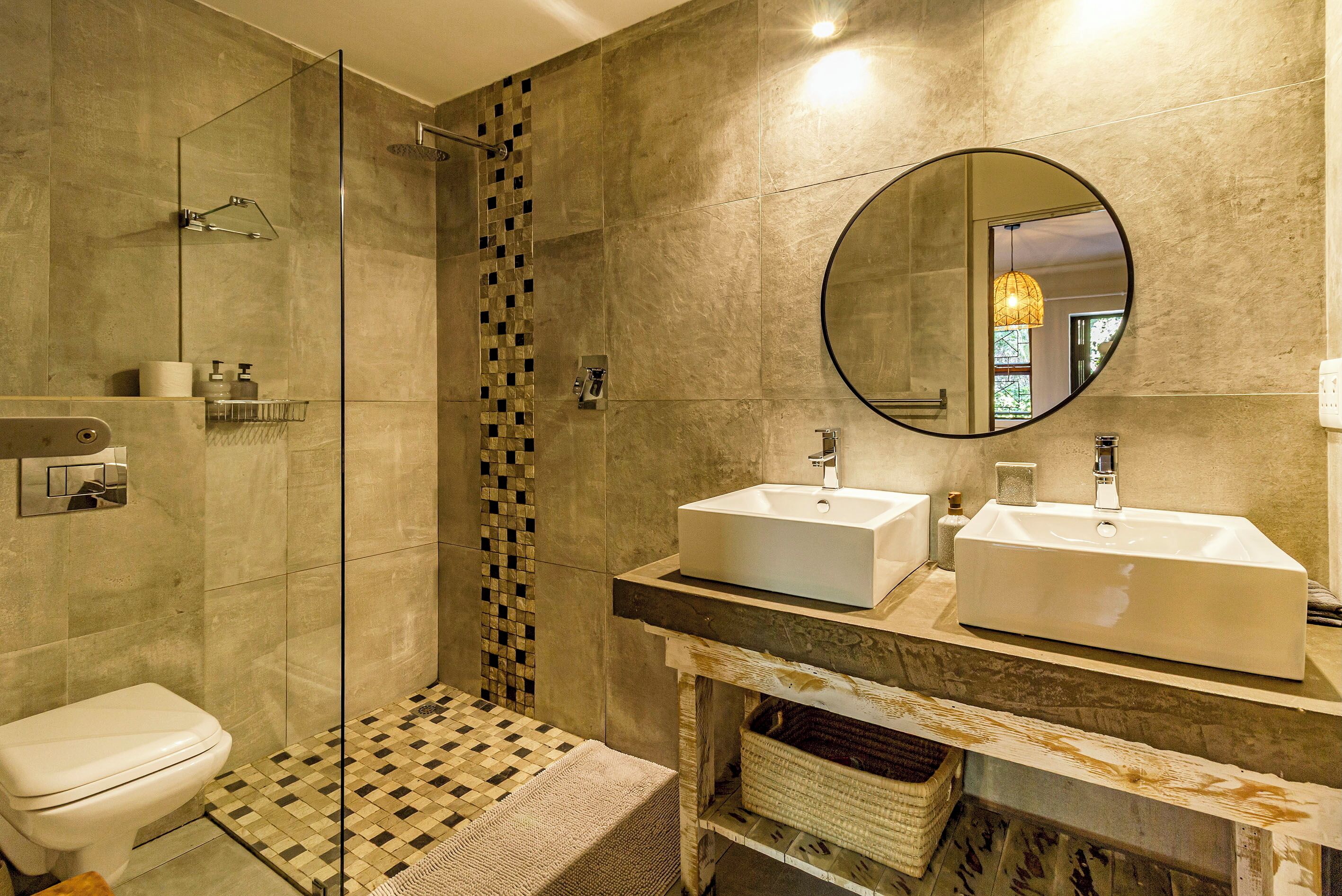 Un bagno moderno con cabina doccia in vetro, due lavabi, un water e pavimento a scacchi.