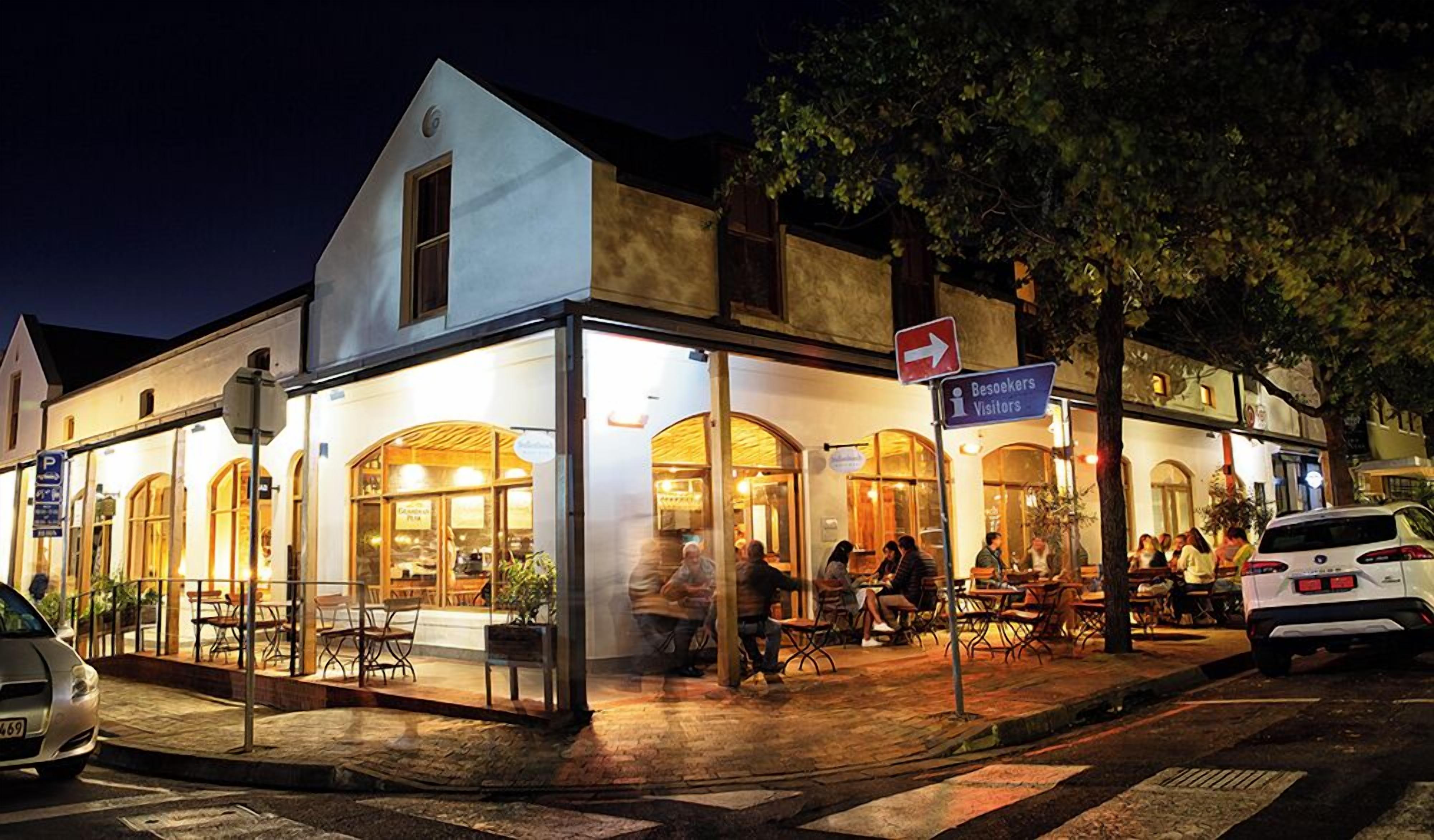 A building with a glass facade, outdoor seating, and a sign for visitors.