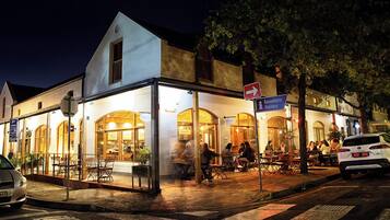 A building with a glass facade, outdoor seating, and a sign for visitors.