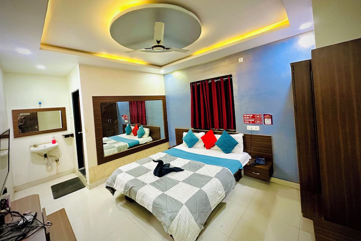A hotel room with a bed, a mirror, a bedside table, a nightstand, a wardrobe, and a reception sign.