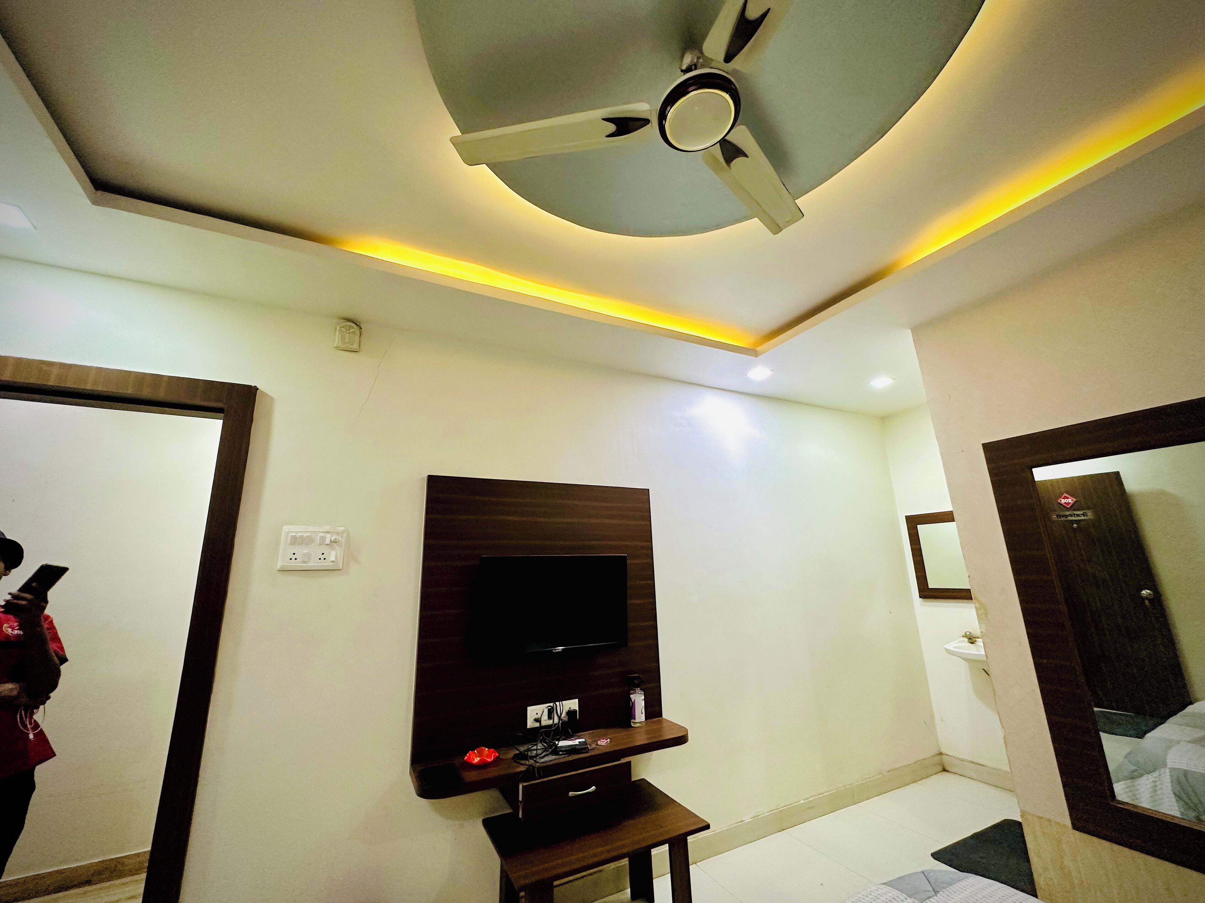Un bagno moderno con una ventola a soffitto, un televisore a parete e uno specchio.