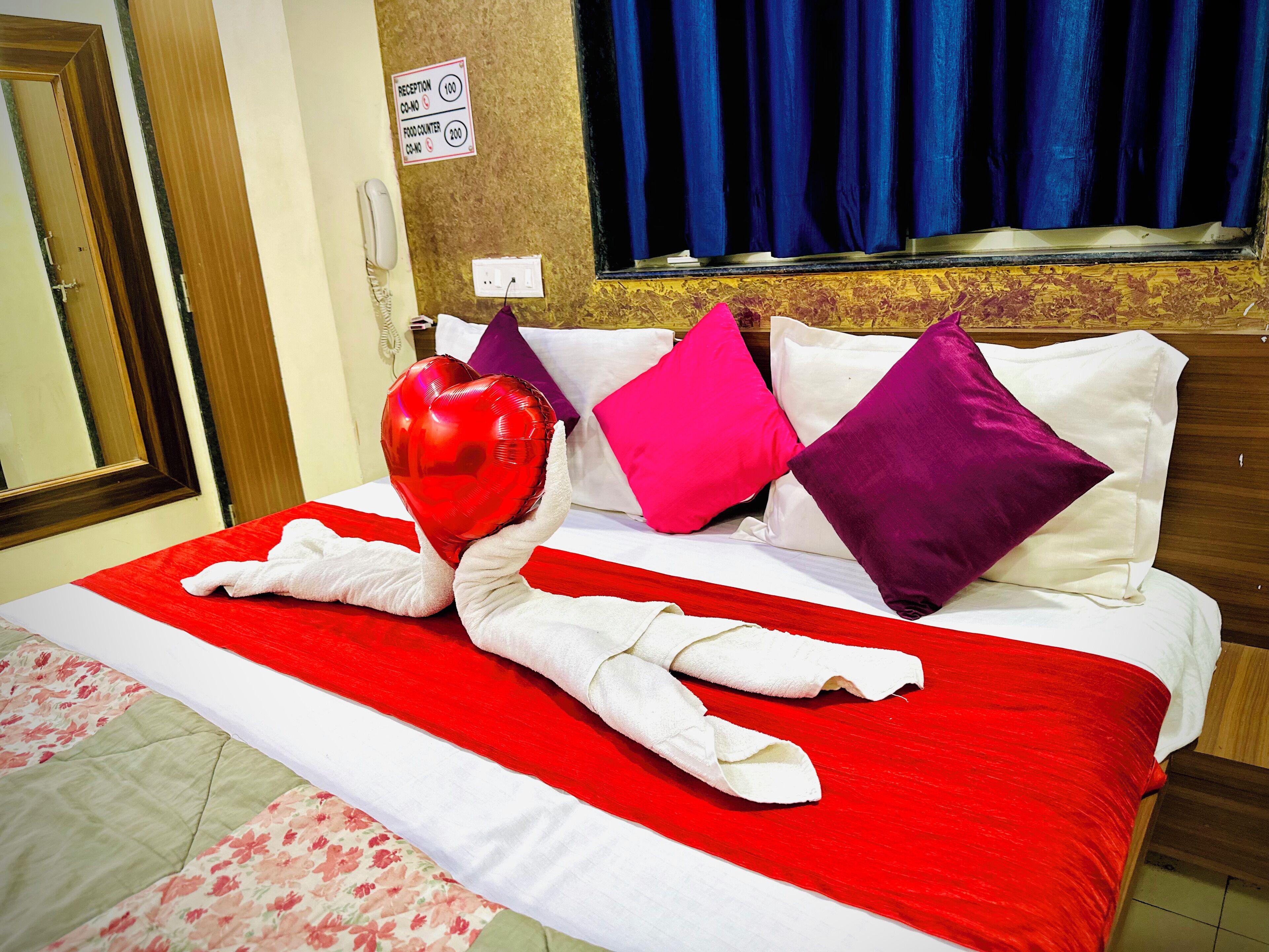 A hotel room with a bed, a reception sign, and a window with curtains.