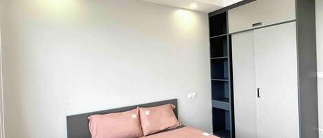 A bedroom with a bed, a wardrobe, and a ceiling light.