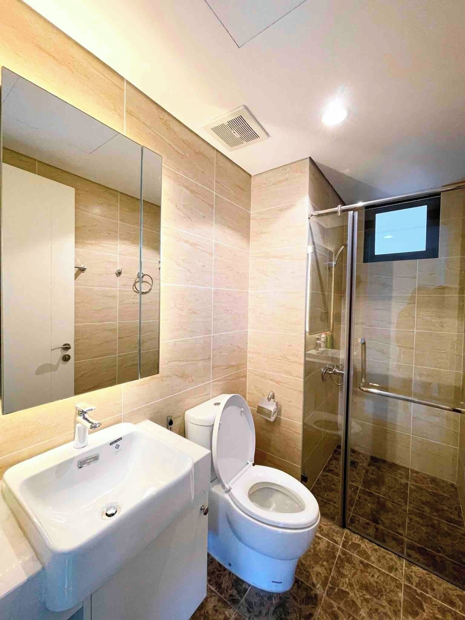 A modern bathroom with a sink, toilet, and glass shower enclosure.