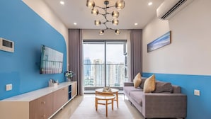 Ein modernes Wohnzimmer mit einem grauen Sofa, einem Holztisch und einem großen Fenster mit Blick auf die Stadt.