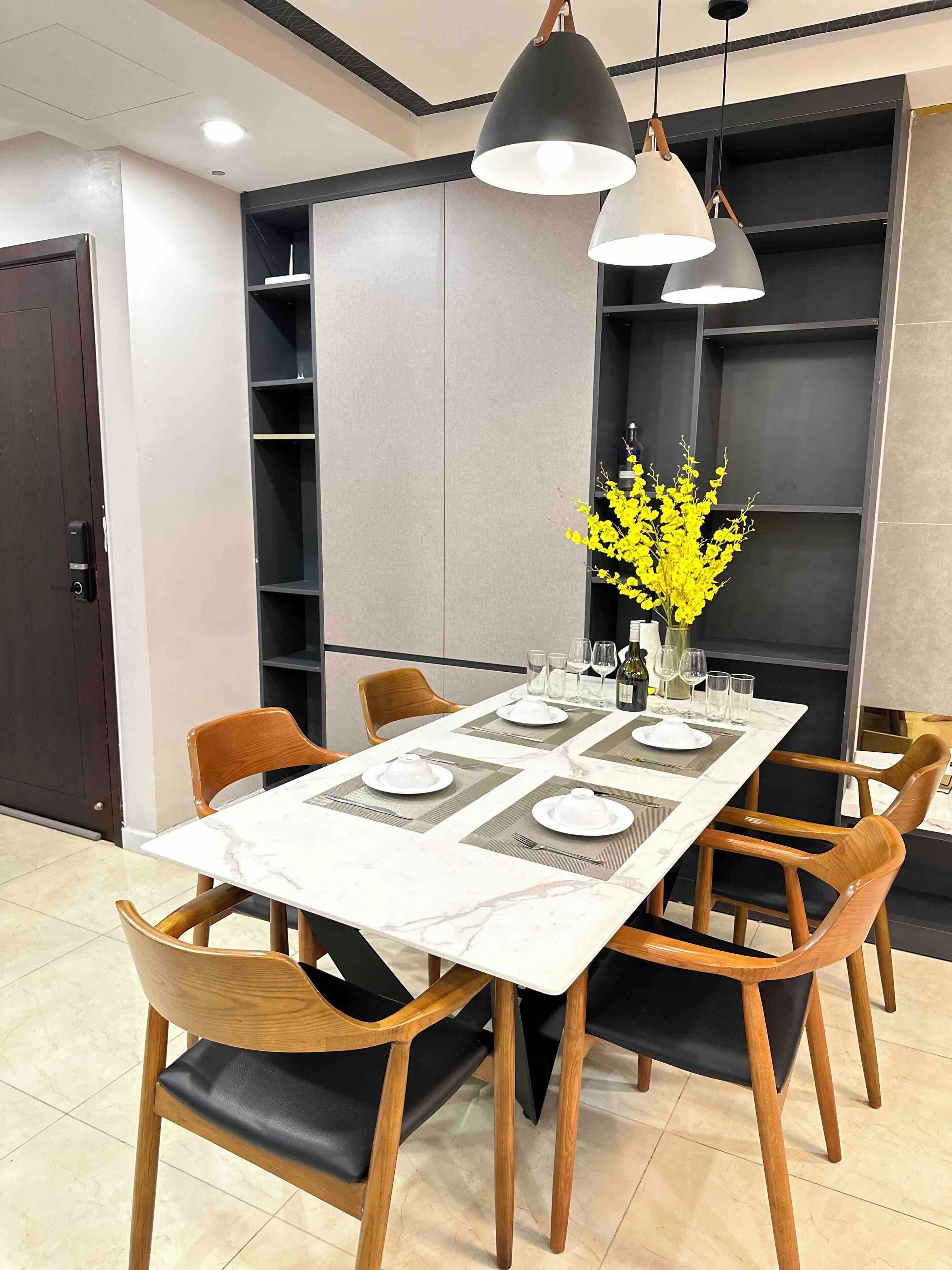 A dining area with a marble table set for four, surrounded by wooden chairs.