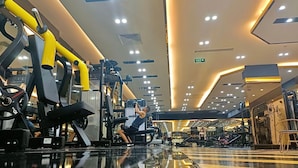 Ein Fitnessstudio mit verschiedenen Trainingsgeräten, einem glatten Boden und einer Decke mit eingelassener Beleuchtung.