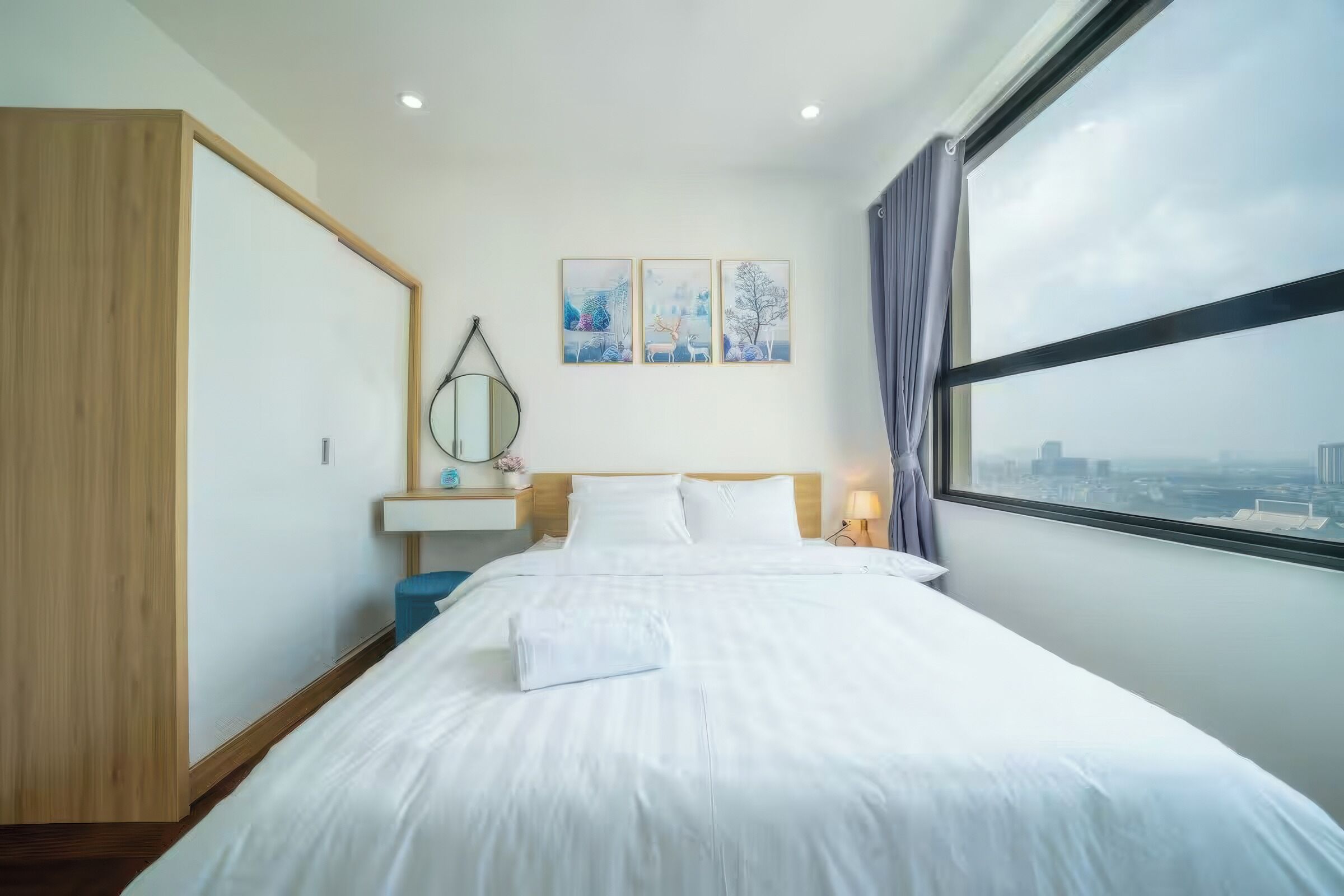 Een hotelkamer met een groot bed, een nachtkastje, een spiegel en een raam met uitzicht op de stad.