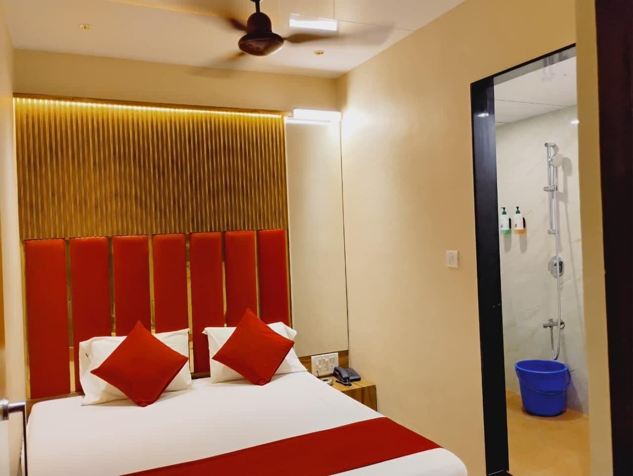 A hotel room with a bed, a nightstand, a mirror, and a shower area.