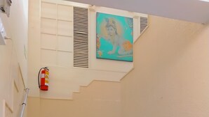 Uma escadaria com degraus cinzentos e um extintor fixado na parede.