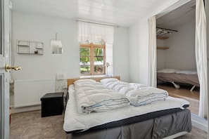 A bedroom with a bed, a window, a radiator, a bedside table, and a wardrobe.