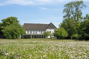 A large white building with a tiled roof, surrounded by a field of white flowers and trees. - Large holiday home near Tønder (Tønder)