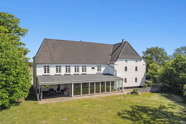 A two-story house with a covered patio, a tiled roof, and a fenced yard. - Large holiday home near Tønder (Tønder)