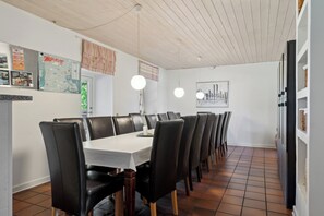 A dining area with a long table, black chairs, and hanging pendant lights. - Large holiday home near Tønder (Tønder)