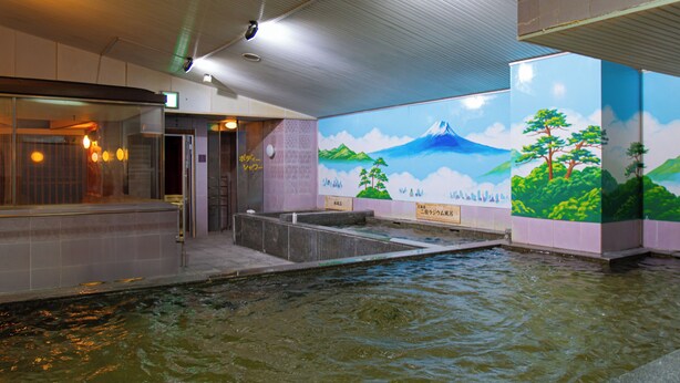 A public bath area with a mural of a mountain and trees, tiled walls, and a water feature. - Men's only Capsule Hotel Asahi Plaza Shinsaibashi (Osaka)