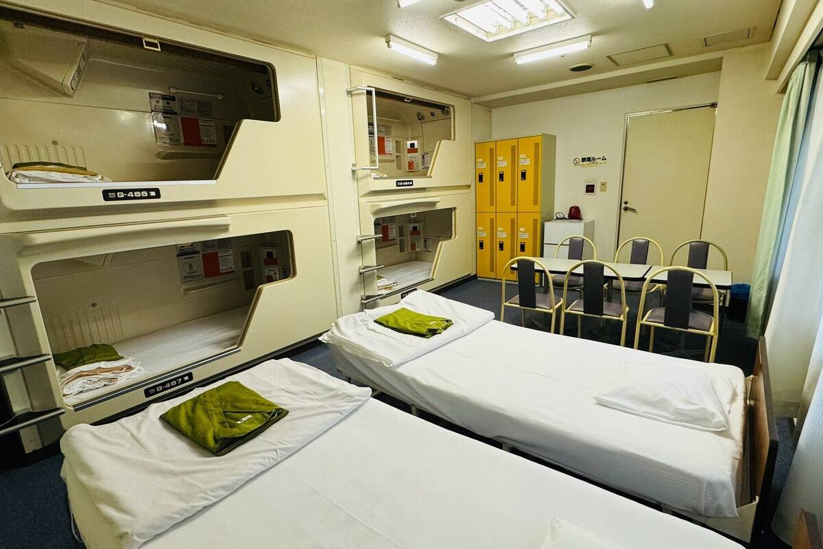 A hospital room with two beds, a desk, chairs, and a cabinet.