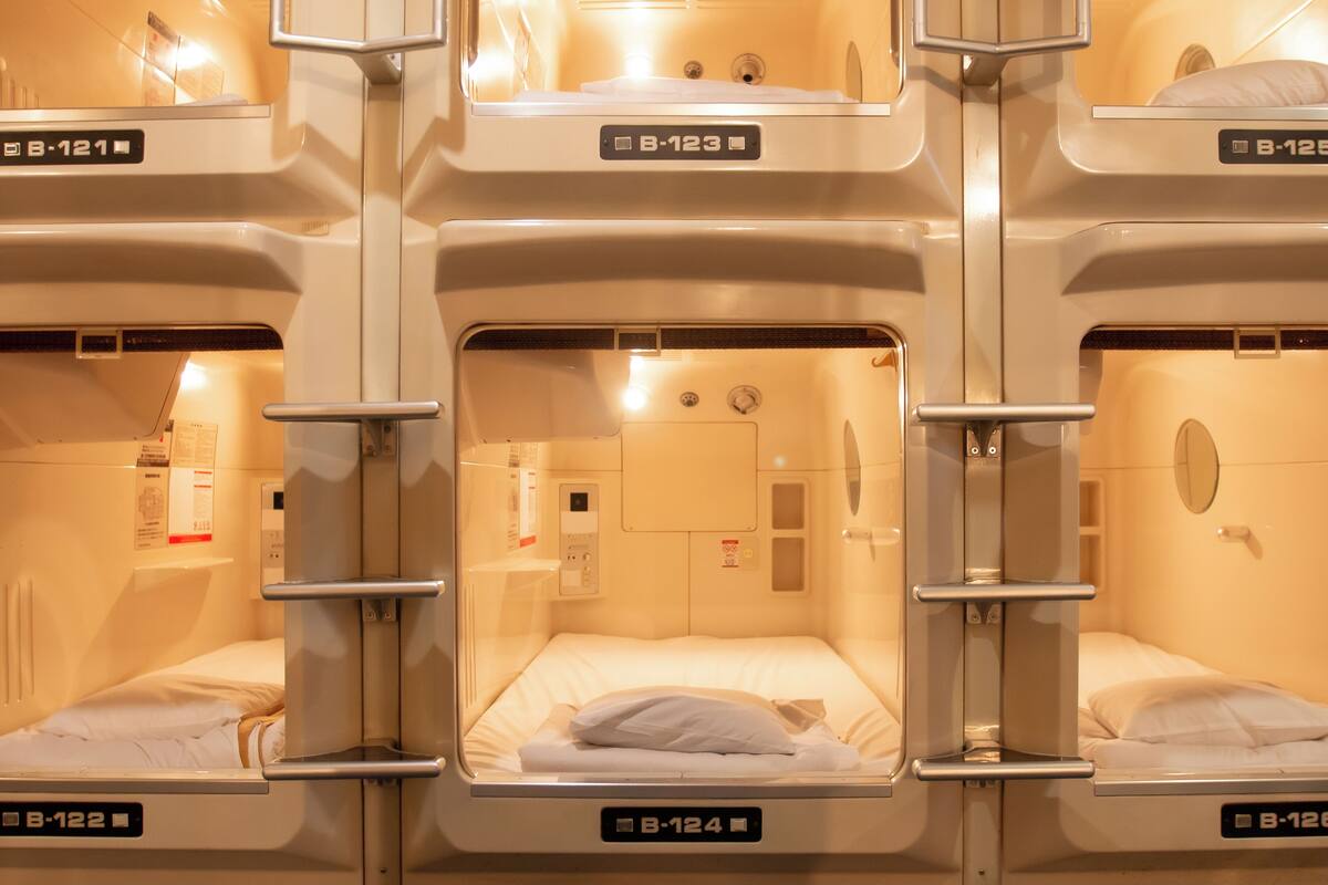 A row of bunk beds in a room with a control panel and a small window.