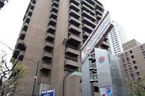 Un immeuble de grande hauteur, doté de nombreux balcons, et sur lequel on peut lire l’enseigne « Blue Thrift » au rez-de-chaussée.