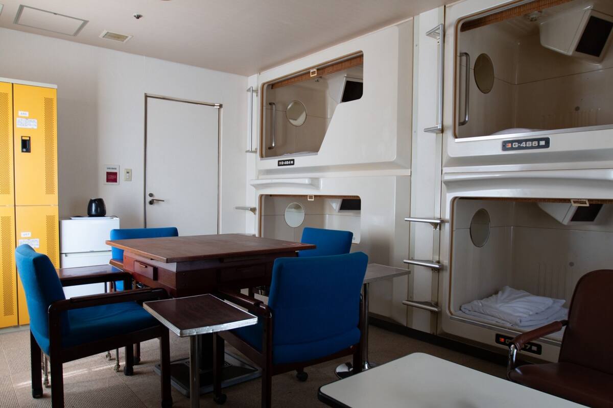 A room with bunk beds, a table, chairs, and a desk.