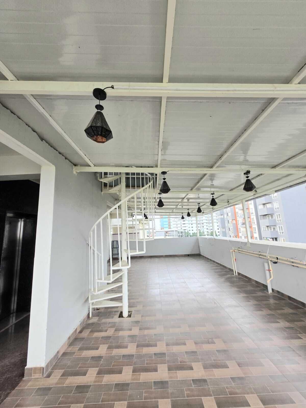 An empty room with a tiled floor, white walls, a spiral staircase, and hanging pendant lights.