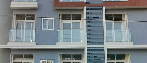 A multi-story building with balconies, large windows, and a storefront at the ground level.
